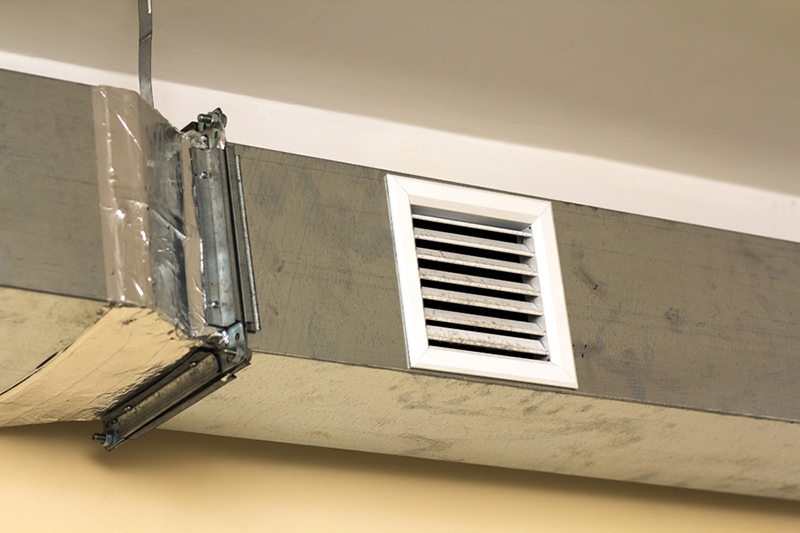 leaky ducts and you Ventilation pipes in silver insulation material hanging from the ceiling inside new building.