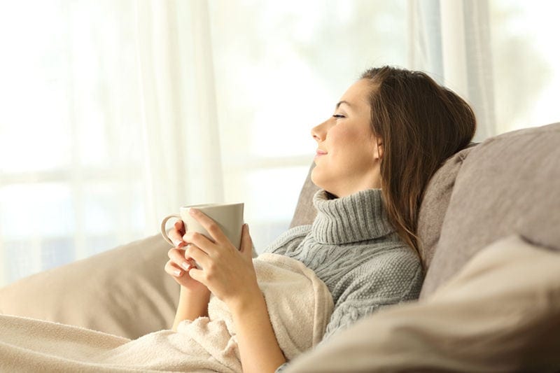 Pensive woman relaxing at home in winter