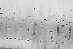 Black and white background of the condensate flowing water on the window glass.
